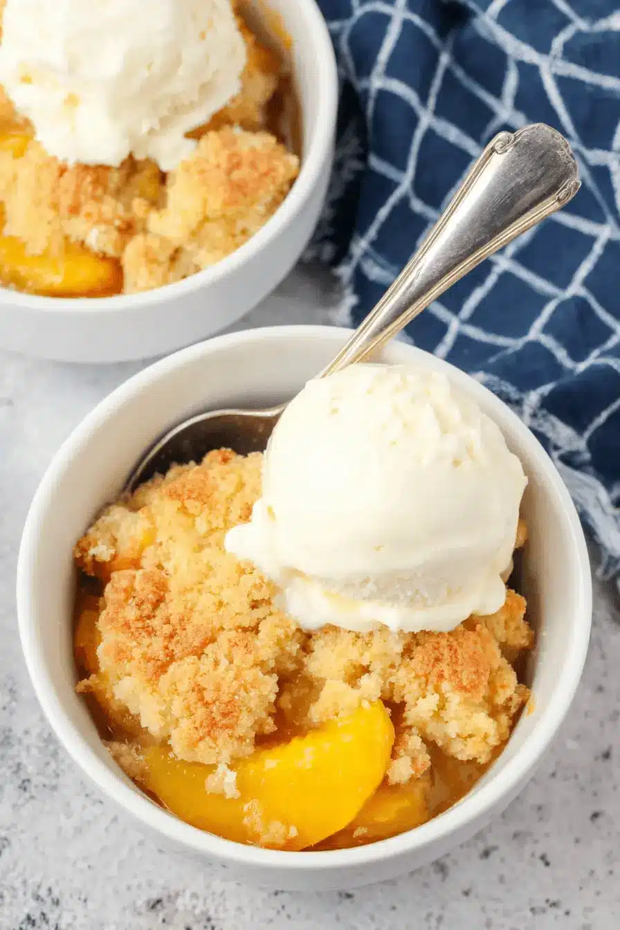 Amazing Canned Peach Cobbler Recipe 2 Two inviting bowls of warm canned peach cobbler recipe, each generously topped with melting vanilla ice cream and a golden-brown crumble.