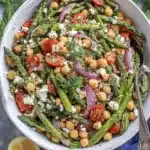 Vibrant Roasted Asparagus Salad: Easy & Fresh 5 Vibrant roasted asparagus salad in a rustic ceramic bowl, featuring chickpeas, cherry tomatoes, feta, and fresh dill, with lemons and raw asparagus spears.