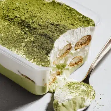 Spectacular Matcha Tiramisu: Easy No-Bake Recipe 4 Close-up of a layered matcha tiramisu with a rose gold spoon scooping out a portion, highlighting its vibrant green matcha powder and creamy texture.