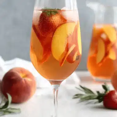 Fantastic Easy Non-Alcoholic Peach Sangria Recipe 4 Refreshing peach sangria with strawberries in a glass, perfect for a summer peach sangria recipe.