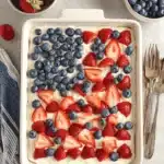 Vibrant & Easy 4th of July Cake Recipe 7 A festive 4th of July cake decorated with strawberries and blueberries in an American flag pattern.