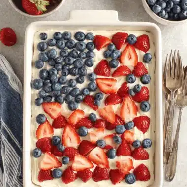 Vibrant & Easy 4th of July Cake Recipe 4 A festive 4th of July cake decorated with strawberries and blueberries in an American flag pattern.
