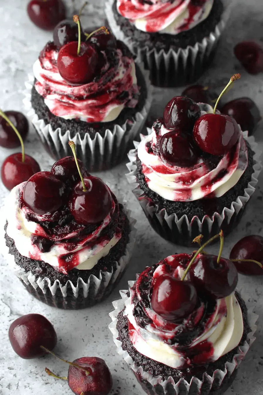 Simple Chocolate Cherry Cupcakes Recipe 2 Four decadent chocolate cherry cupcakes with white frosting, cherry compote, and fresh cherries on a stone surface.