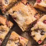 The Ultimate Foolproof Rhubarb Cake 7 Close-up of rustic rhubarb cake slices dusted with powdered sugar on a wooden surface.