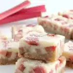 Amazing Foolproof Rhubarb Bars 6 Close-up of freshly baked rhubarb bars with a golden shortbread crust, creamy rhubarb filling, and a dusting of powdered sugar, presented with fresh rhubarb stalks.