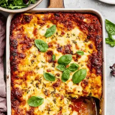 Ultimate Foolproof Zucchini Lasagna Recipe 4 Freshly baked zucchini lasagna recipe, golden brown with bubbly cheese and fresh basil, served in a white baking dish.