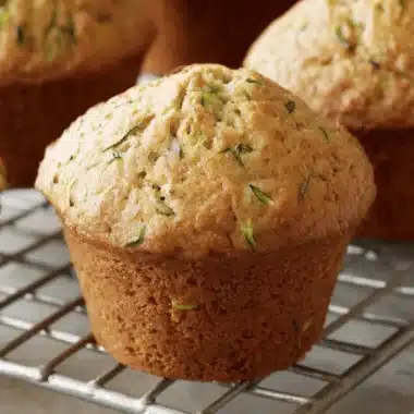 Perfect Zucchini Muffins: Easy & Moist 3 Freshly baked golden-brown zucchini muffins cooling on a wire rack.