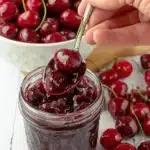 Amazing Easy Cherry Preserves Recipe 5 Glass jar of homemade cherry preserves with a spoon, highlighting a delicious cherry preserves recipe.