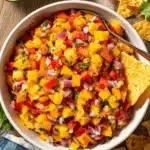 Amazing Fresh Peach Mango Salsa Recipe 8 Vibrant overhead shot of fresh peach mango salsa with tortilla chips and lime on a rustic wooden surface.