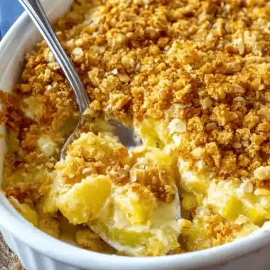 Ultimate Yellow Squash Casserole: Perfectly Creamy 19 Close-up of a delicious, golden-brown yellow squash casserole in a white baking dish with a spoon.