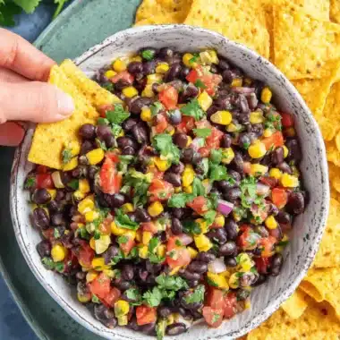 Amazing Black Bean and Corn Salsa Recipe 4 Vibrant black bean and corn salsa in a rustic bowl, ready to be scooped with golden tortilla chips.