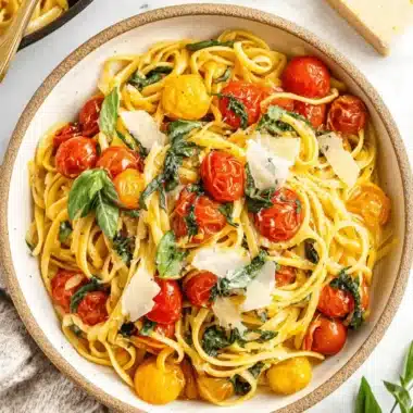 Amazing Foolproof Cherry Tomato Pasta 4 Close-up of creamy cherry tomato pasta with blistered tomatoes, fresh basil, and shaved Parmesan in a rustic bowl.