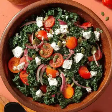 Vibrant Kale Tomato Salad: Simple & Terrific 4 Vibrant kale tomato salad with feta, red onion, and pumpkin seeds in a rustic wooden bowl.
