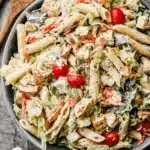 Amazing Ceasar Pasta Chicken Salad 5 Close-up overhead view of a vibrant ceasar pasta chicken salad with penne, grilled chicken, and fresh vegetables in a rustic grey bowl.