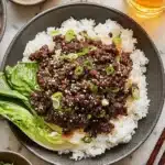 Amazing Korean Beef Bowl: Ready in Under 20 Mins 5 Top-down view of a delicious Korean Beef Bowl with savory ground beef, fluffy rice, bok choy, and garnishes on a marble countertop.