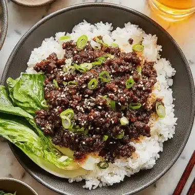 Amazing Korean Beef Bowl: Ready in Under 20 Mins 4 Top-down view of a delicious Korean Beef Bowl with savory ground beef, fluffy rice, bok choy, and garnishes on a marble countertop.