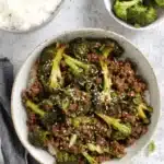 Fantastic Ground Beef and Broccoli Dinner 6 Top-down view of a rustic bowl featuring a delicious Ground Beef and Broccoli stir-fry served over white rice, garnished with sesame seeds and green onions.