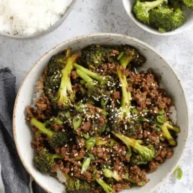 Fantastic Ground Beef and Broccoli Dinner 3 Top-down view of a rustic bowl featuring a delicious Ground Beef and Broccoli stir-fry served over white rice, garnished with sesame seeds and green onions.