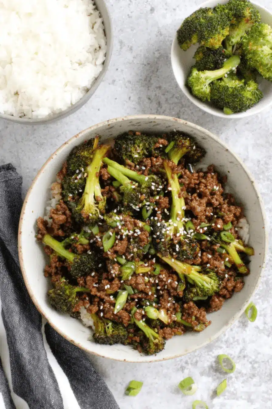 Fantastic Ground Beef and Broccoli Dinner 2 Top-down view of a rustic bowl featuring a delicious Ground Beef and Broccoli stir-fry served over white rice, garnished with sesame seeds and green onions.