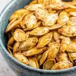 The Ultimate Pumpkin Seeds Recipe: Crunchy & Easy 9 Rustic ceramic bowl filled with golden-brown roasted pumpkin seeds, showcasing a delicious pumpkin seeds recipe.