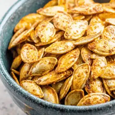 The Ultimate Pumpkin Seeds Recipe: Crunchy & Easy 3 Rustic ceramic bowl filled with golden-brown roasted pumpkin seeds, showcasing a delicious pumpkin seeds recipe.