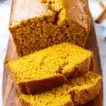 Amazing Pumpkin Bread: Super Moist & Easy Recipe 7 Freshly baked pumpkin bread slices on a rustic wooden board with fall decor.