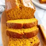 Amazing Foolproof Pumpkin Bread Recipe 5 Freshly sliced pumpkin bread on a wooden cutting board, revealing its moist, vibrant orange interior.