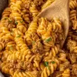 Amazing One-Pot Ground Beef Pasta in 30 Mins 8 Hearty ground beef pasta bake with corkscrew fusilli, creamy tomato sauce, and fresh parsley, served in a dark bowl.