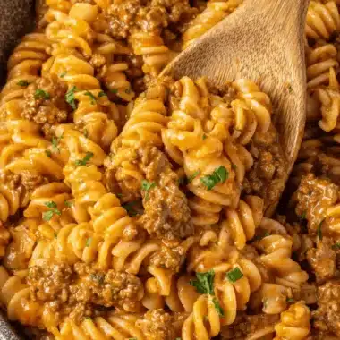 Amazing One-Pot Ground Beef Pasta in 30 Mins 4 Hearty ground beef pasta bake with corkscrew fusilli, creamy tomato sauce, and fresh parsley, served in a dark bowl.