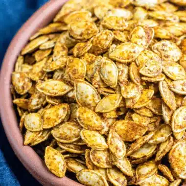 Easy Roasted Pumpkin Seeds Recipe 4 Close-up of a rustic bowl filled with seasoned, roasted pumpkin seeds, perfect for a delicious pumpkin seeds recipe.