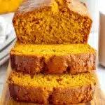 The Ultimate Foolproof Pumpkin Bread 9 Freshly baked pumpkin bread slices on a rustic wooden cutting board.