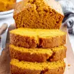 Amazing Pumpkin Bread: Simple & Moist Loaf 8 Freshly baked pumpkin bread loaf, sliced on a rustic wooden board, showing its moist texture, rich orange color, and sparkling sugar topping.
