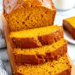 Unbelievably Moist Pumpkin Bread Recipe 6 Close-up of delicious, freshly baked pumpkin bread slices on a wooden cutting board.