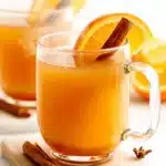 Ultimate Foolproof Apple Cider Recipe 5 Warm apple cider recipe in a clear glass mug with orange slices, cinnamon sticks, and star anise on a wooden and marble coaster.