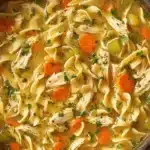 The Ultimate Easy Chicken Noodle Soup 7 Close-up of a steaming bowl of classic chicken noodle soup with tender chicken, wide egg noodles, carrots, and celery.