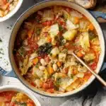 Amazing Cabbage Soup: Easy & Delicious Recipe 6 Hearty cabbage soup with vegetables and cannellini beans in a blue cast iron pot, served with crusty bread.